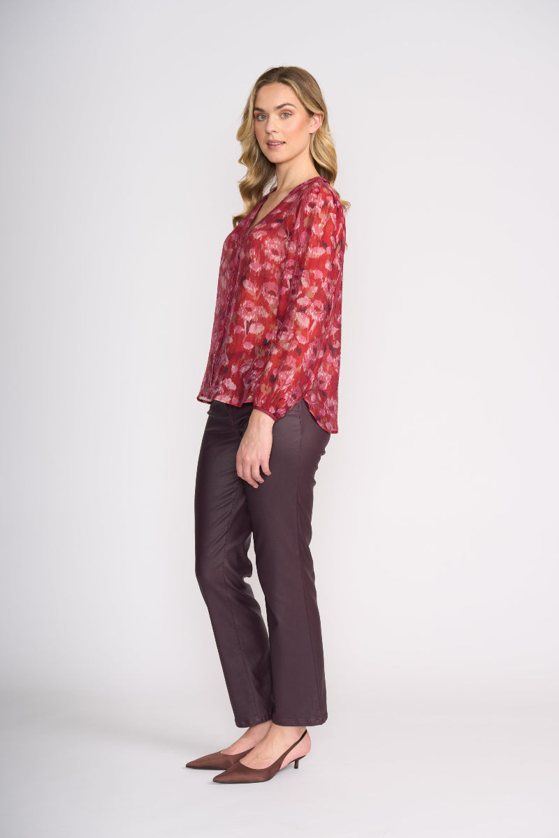 Woman wearing a red floral blouse and brown pants on a white background