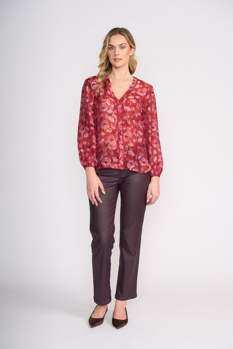 Woman wearing a red floral blouse and brown pants on a white background