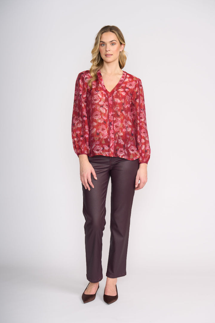 Woman wearing a red floral blouse and brown pants on a white background
