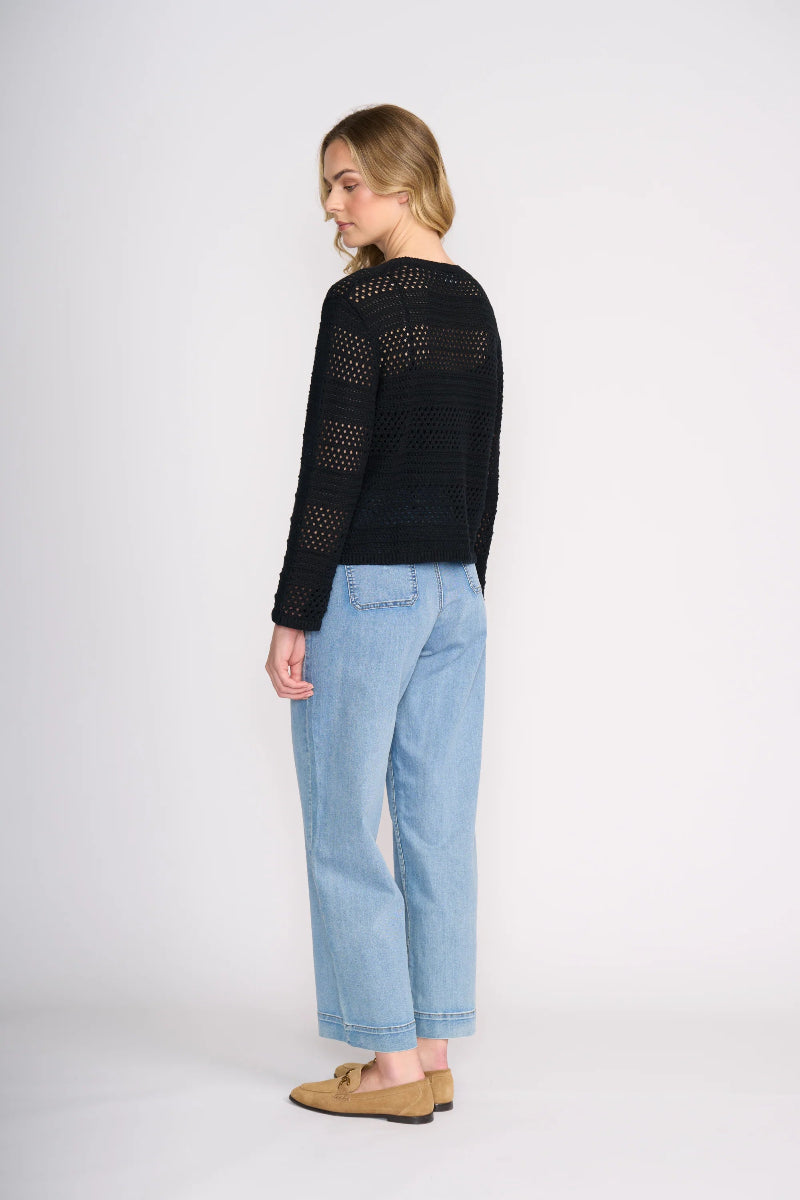 Woman wearing a black sweater and light blue jeans on a white background