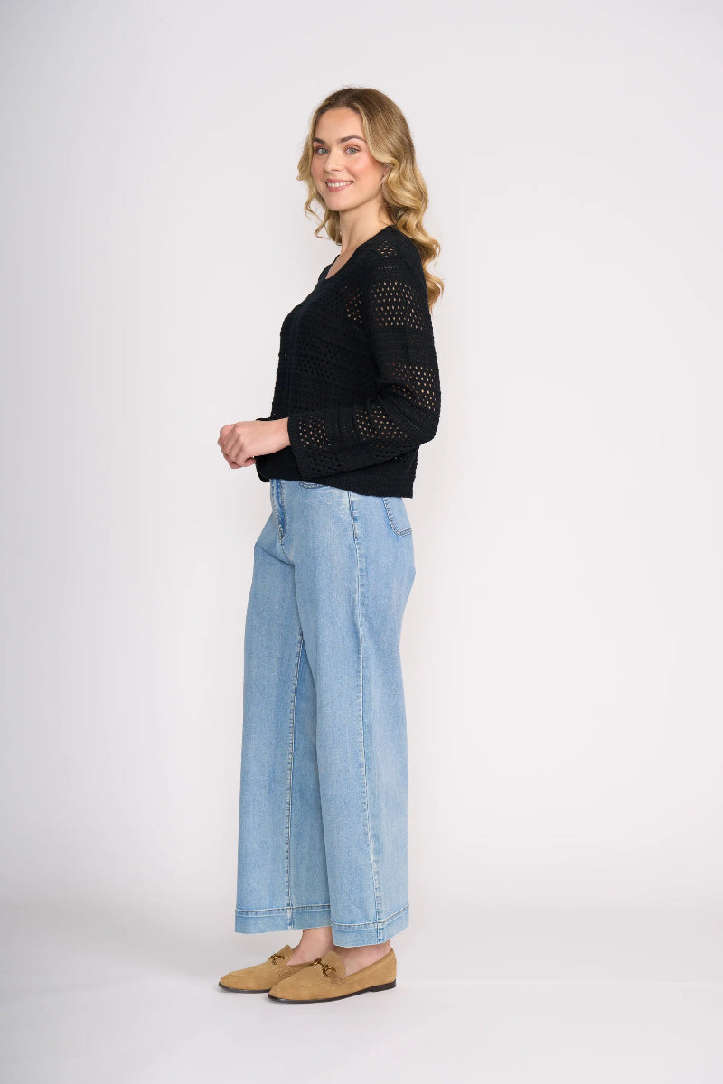 Woman wearing a black top and light blue jeans on a white background