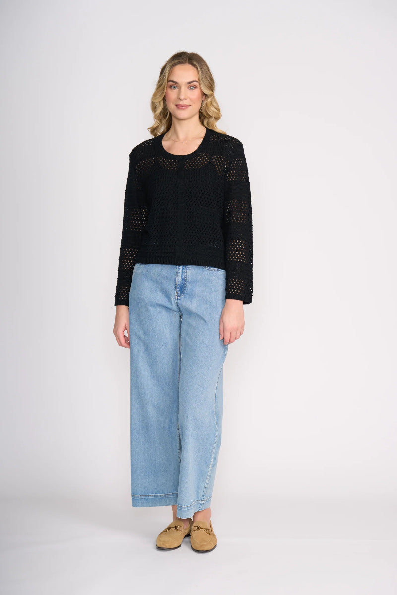 Woman wearing a black sweater and light blue jeans on a white background