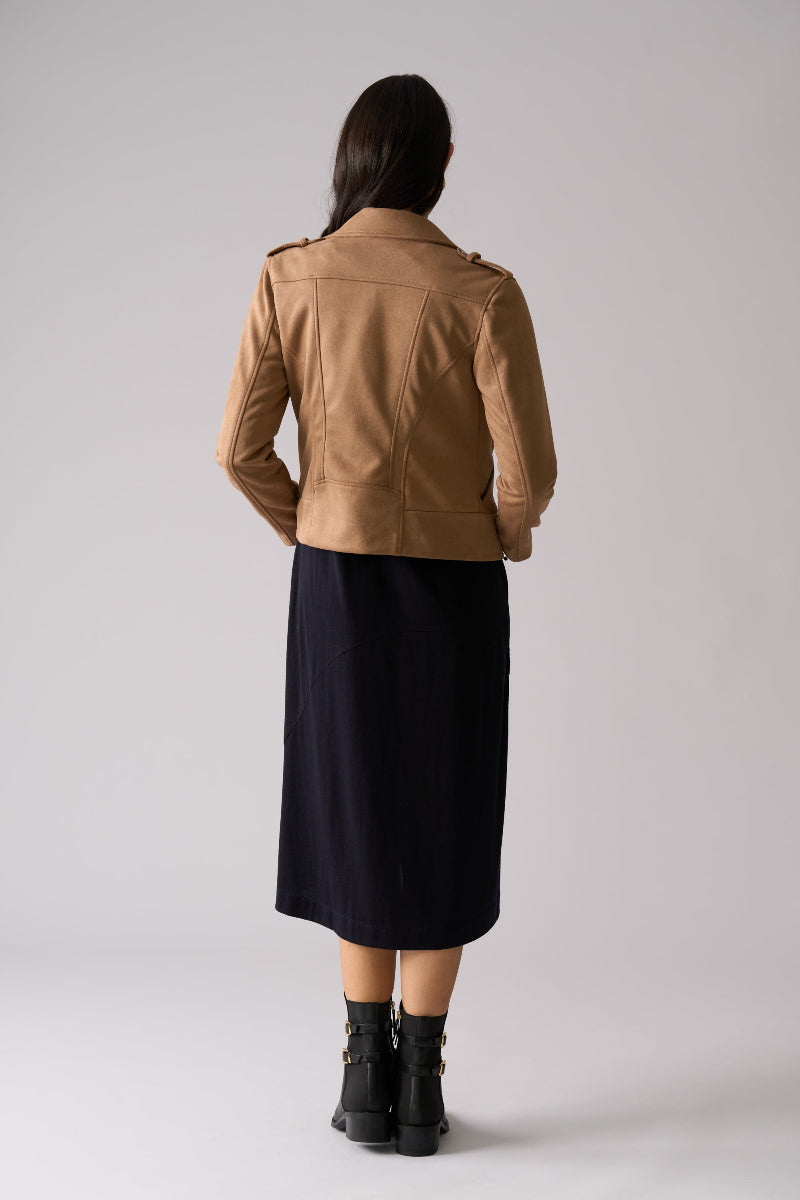 Person wearing a brown leather jacket and black skirt on a white background
