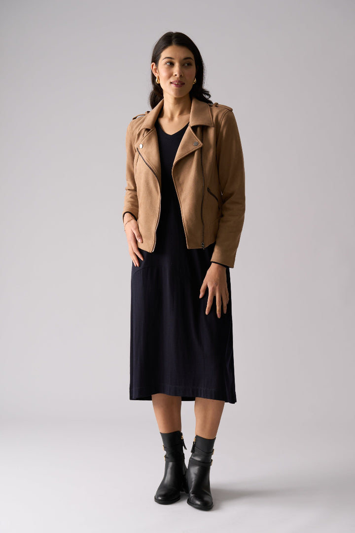 Woman wearing a tan jacket over a black dress on a white background
