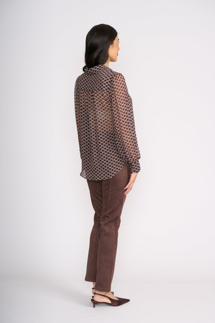 Woman wearing a patterned blouse and brown pants on a white background