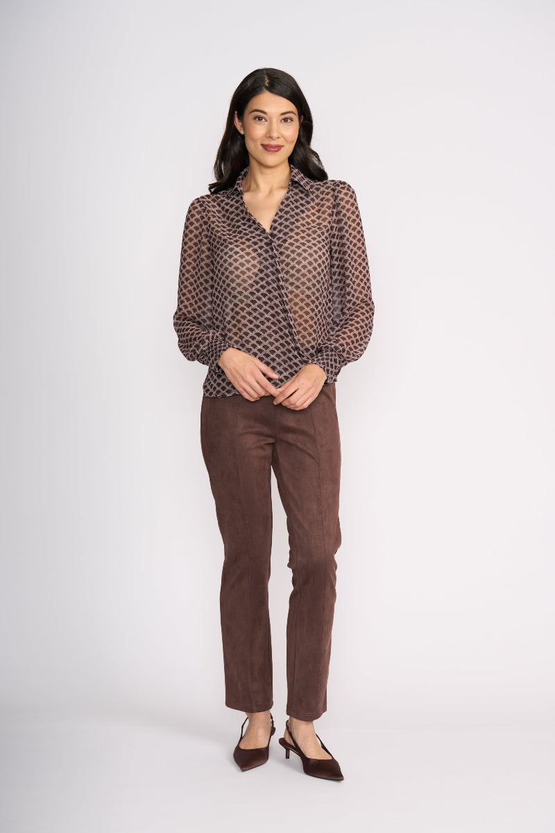 Woman wearing a brown patterned blouse and brown pants on a white background