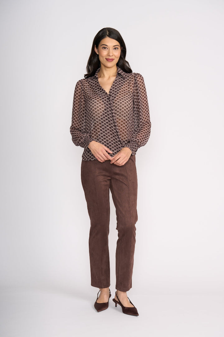 Woman wearing a brown patterned blouse and brown pants on a white background