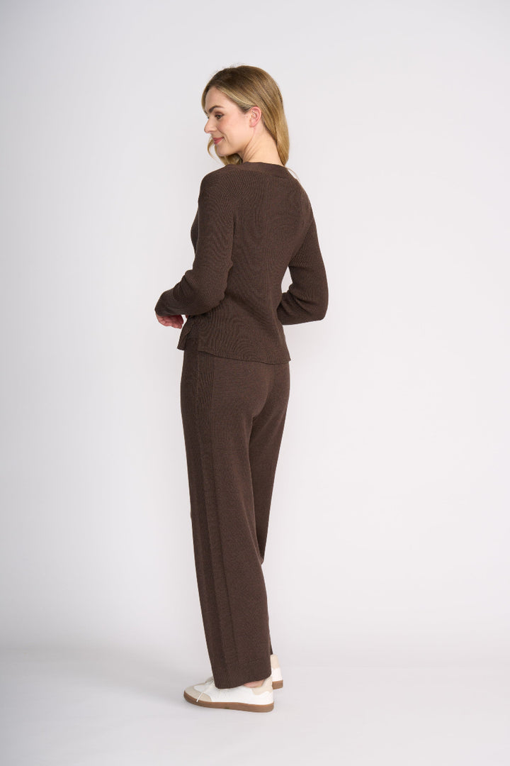 Woman wearing a brown suit standing against a white background