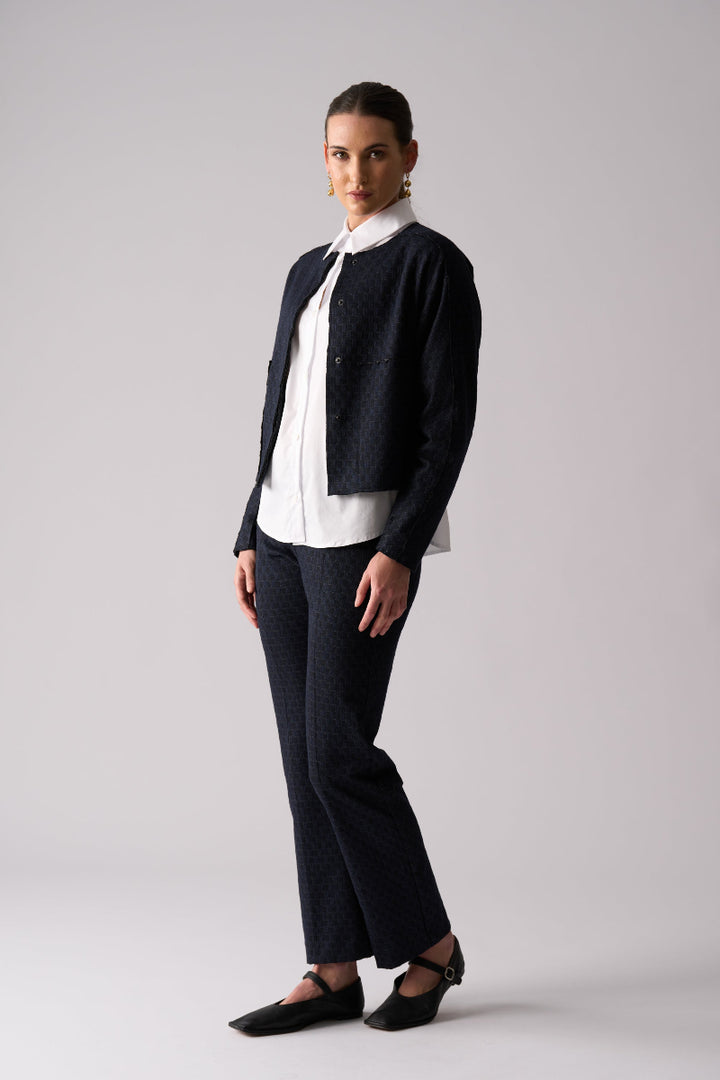 Woman wearing a black cardigan, white blouse, and black pants on a gray background