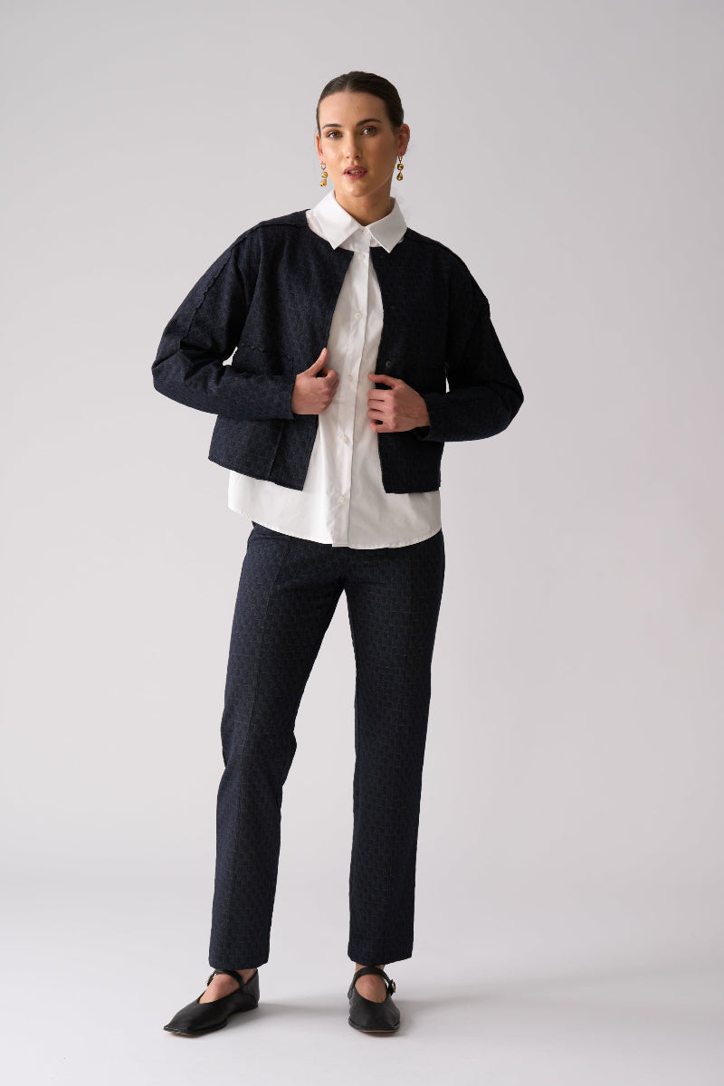 Woman wearing a black jacket, white shirt, and black pants on a white background