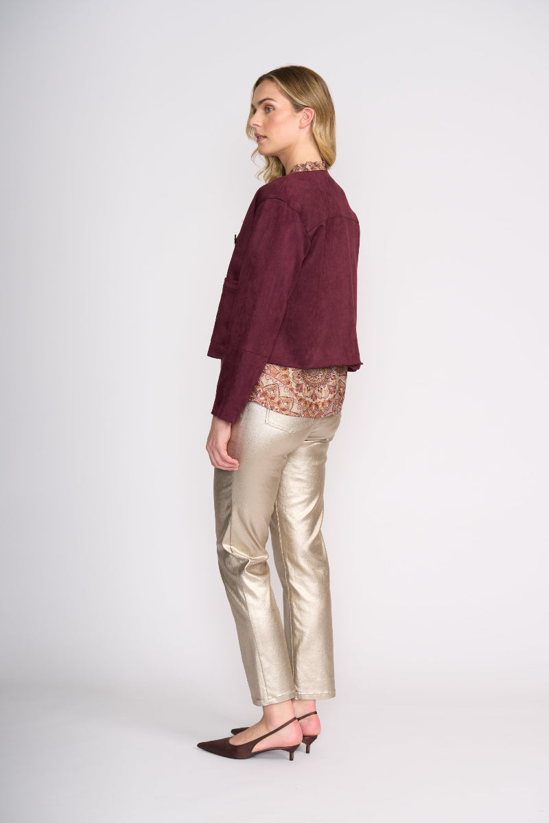 Woman wearing a burgundy top and gold pants on a white background