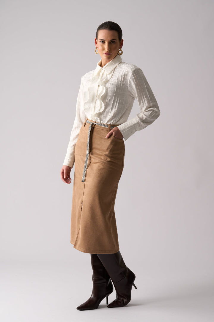 Woman wearing a white blouse and tan skirt on a plain background