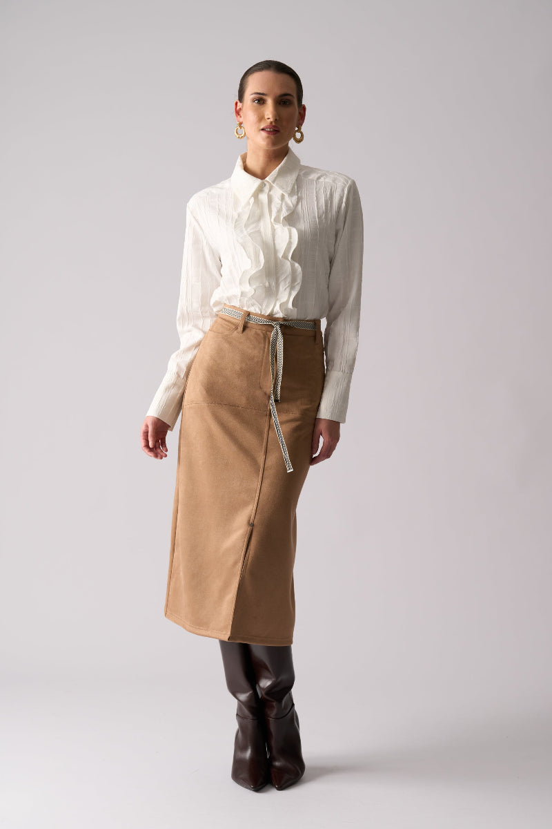 Woman wearing a white blouse and tan skirt on a plain background