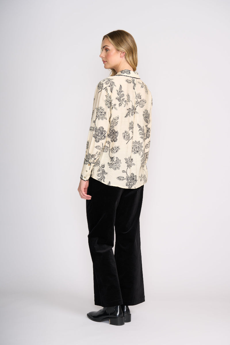 Woman wearing a floral blouse and black pants on a white background