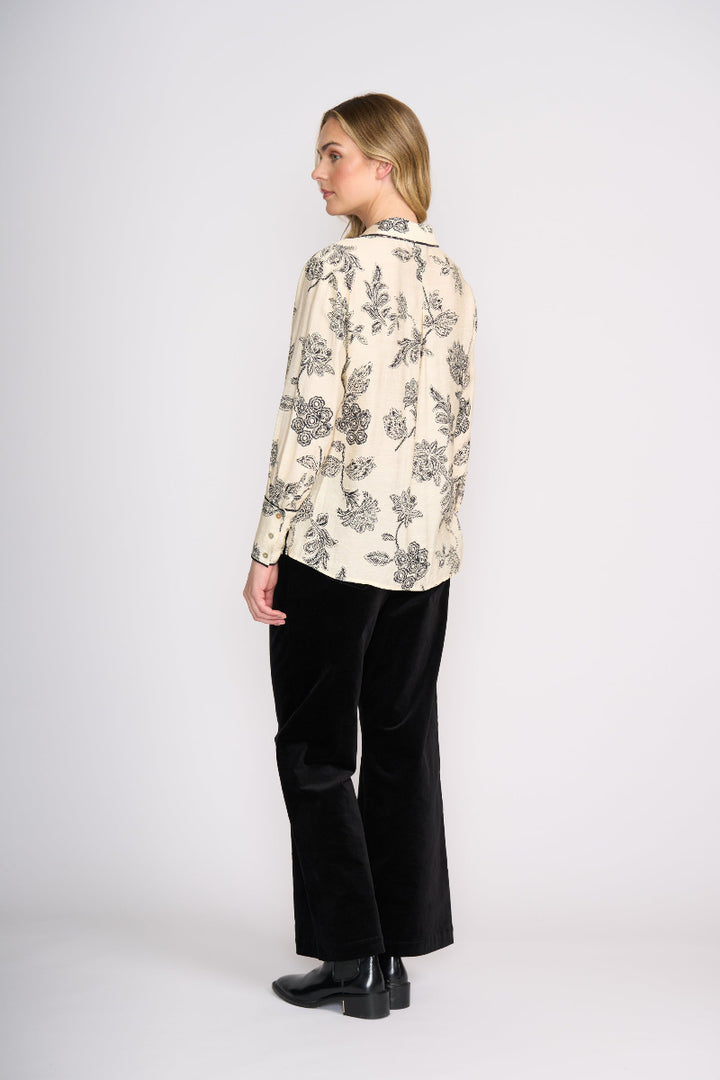Woman wearing a floral blouse and black pants on a white background
