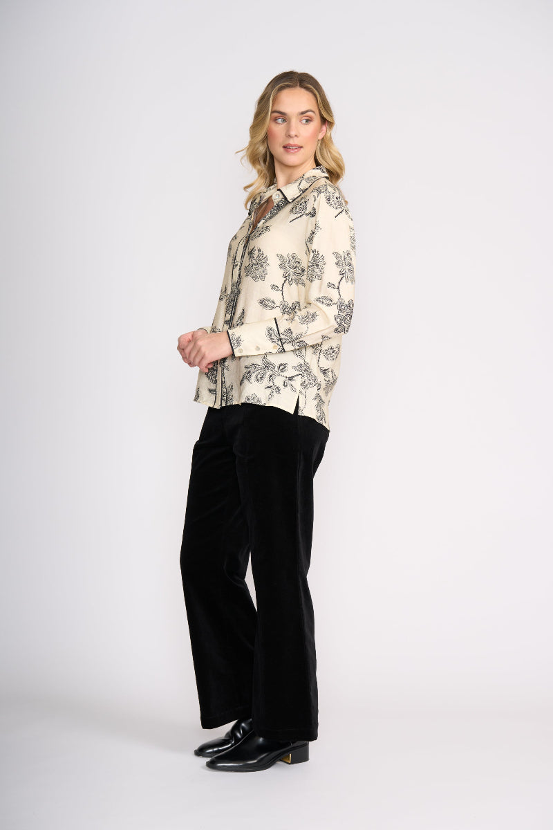 Woman wearing a floral blouse and black pants on a white background