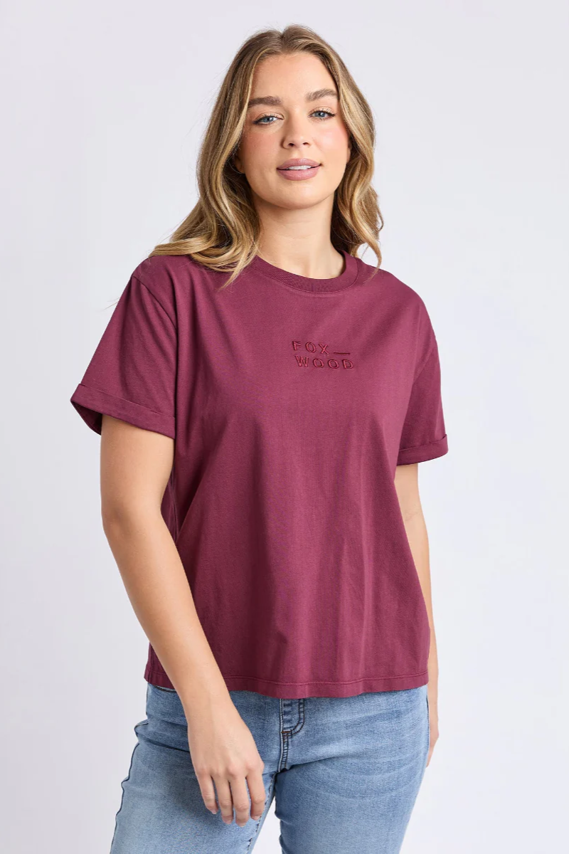Woman wearing a maroon t-shirt with text on a plain background
