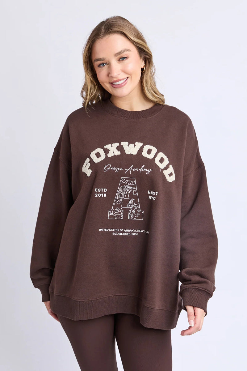 Woman wearing a brown sweatshirt with 'FOXWOOD' branding on a white background