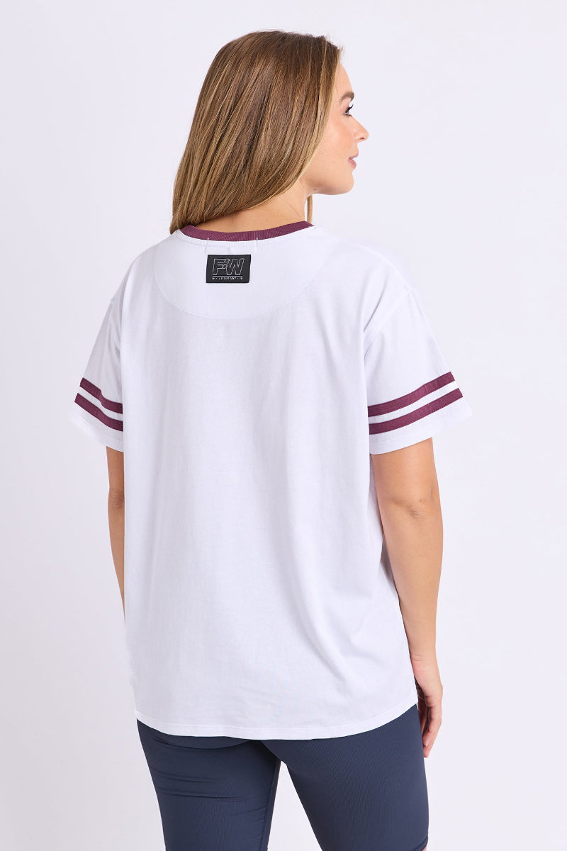 Woman wearing a white t-shirt with maroon accents on a plain background