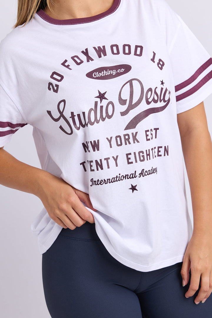 White t-shirt with maroon text and accents worn by a person on a plain background