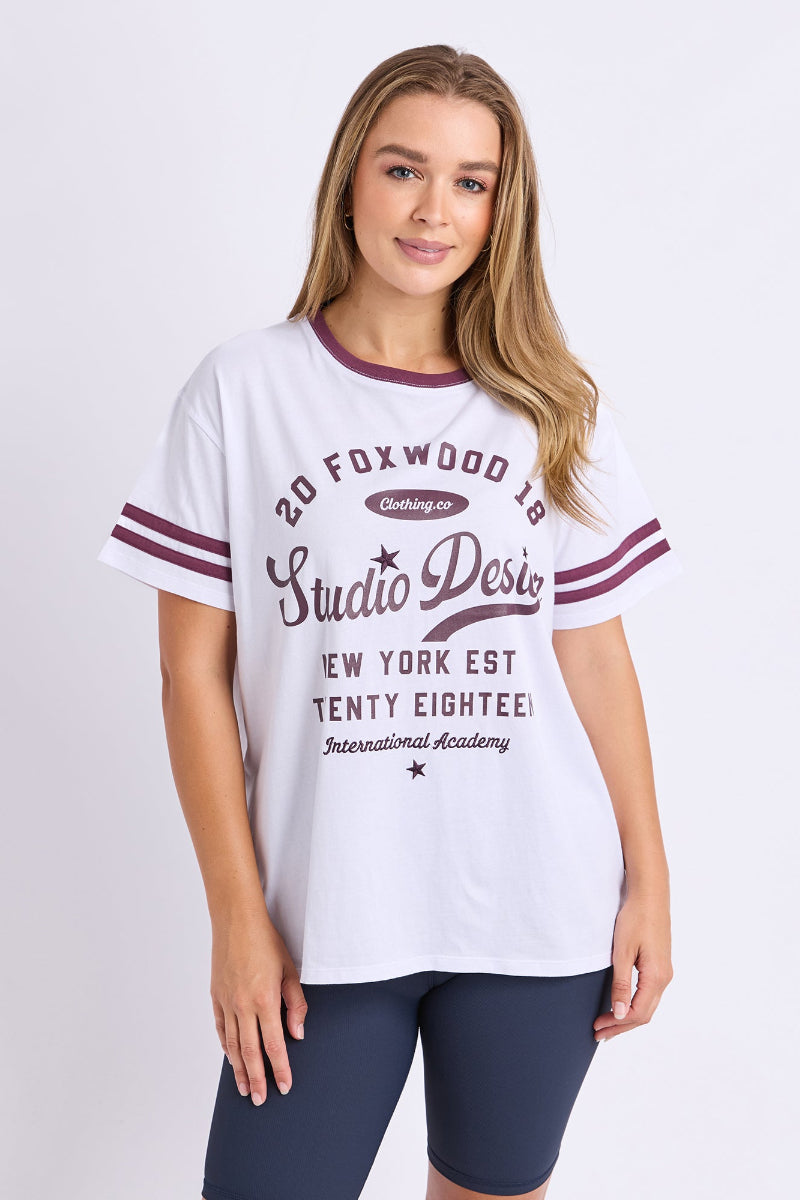 Woman wearing a white t-shirt with maroon accents and text on a plain background