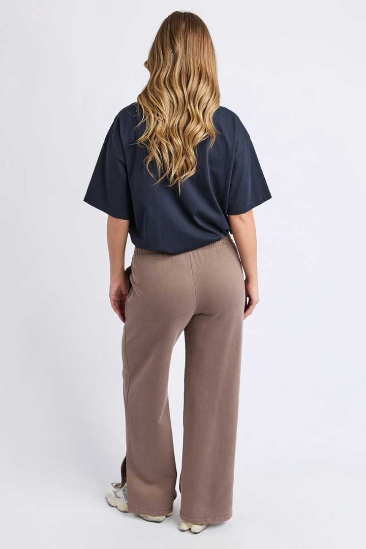Person wearing a navy shirt and beige pants on a white background
