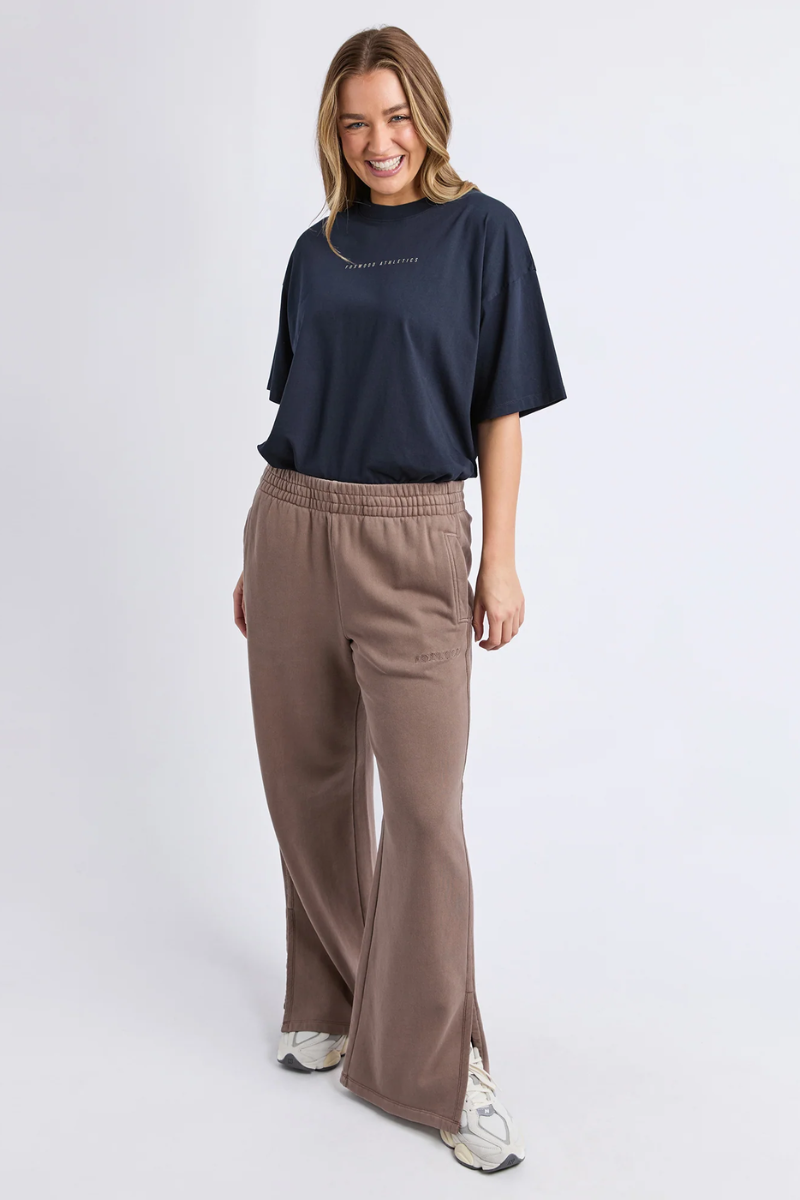 Woman wearing a navy t-shirt and brown pants on a white background