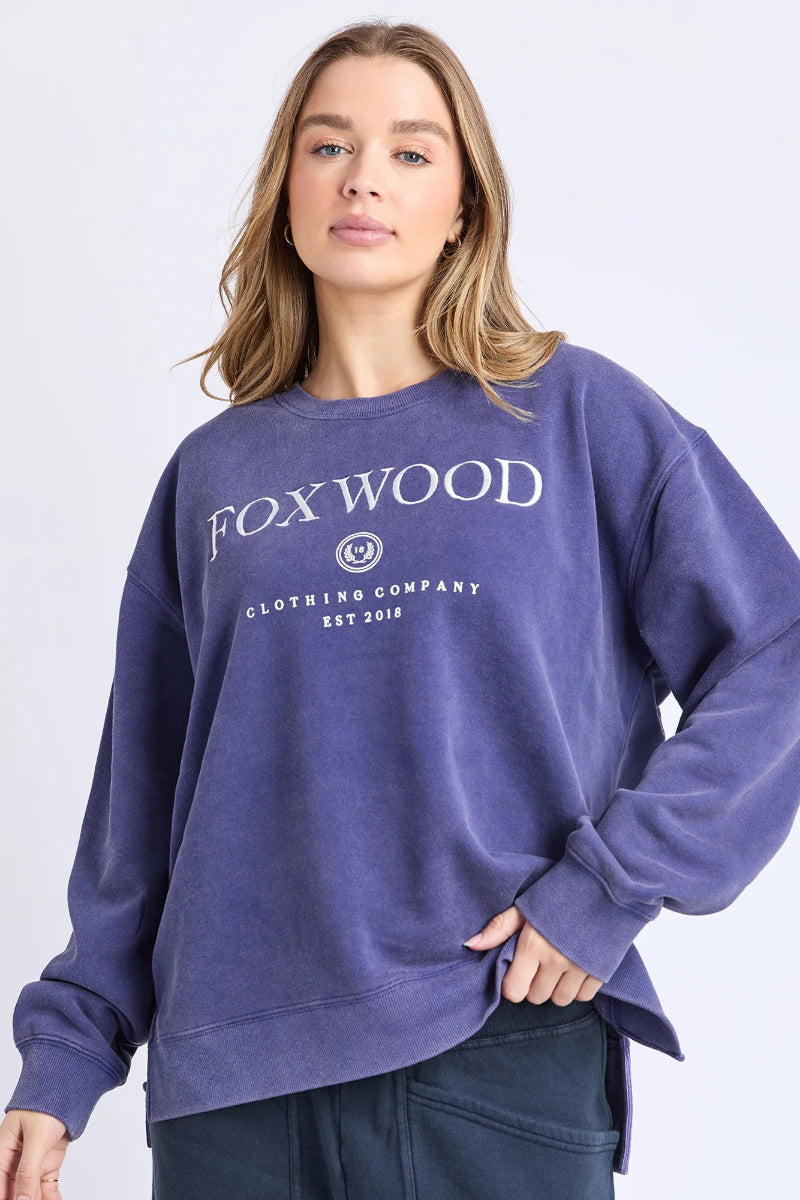 Woman wearing a purple sweatshirt with 'FOX WOOD' branding on a light gray background