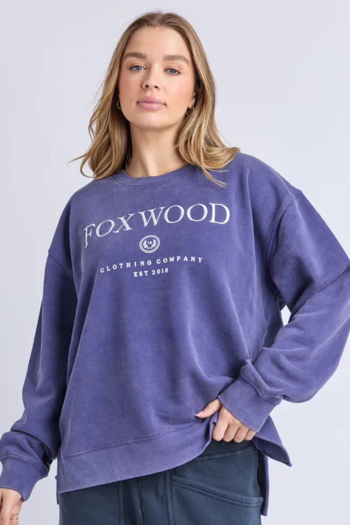 Woman wearing a purple sweatshirt with 'FOX WOOD' branding on a light gray background