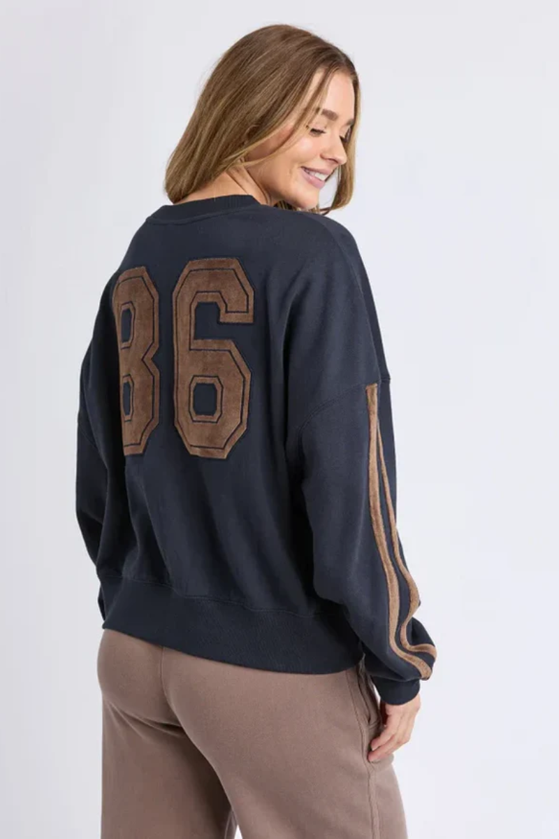 Person wearing a navy sweatshirt with '86' on the back against a white background