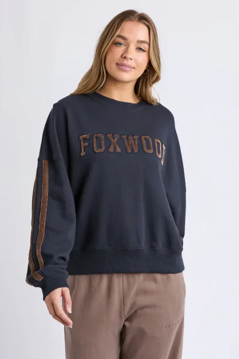Woman wearing a navy sweatshirt with 'FOXWOOD' text on a plain background