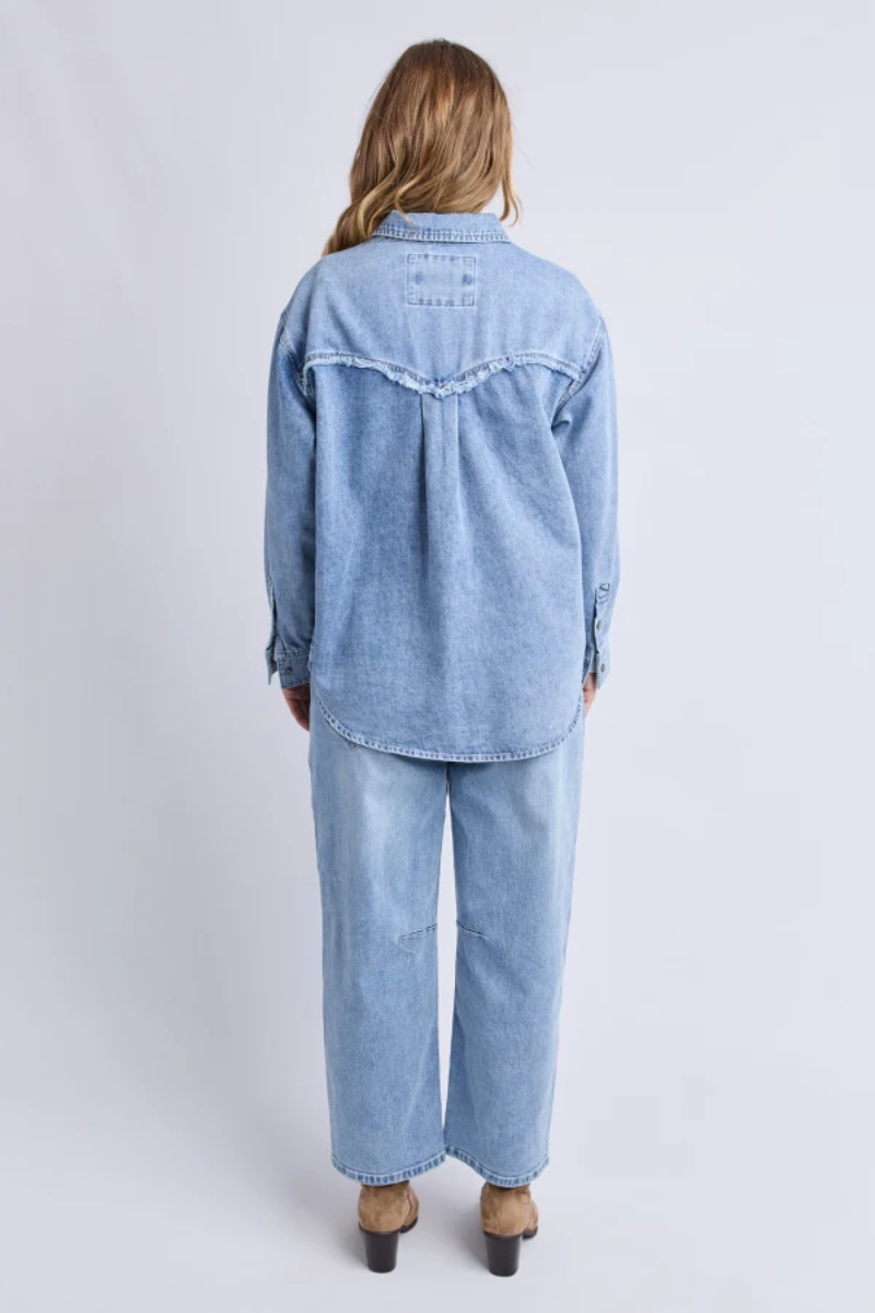 Person wearing a light blue denim outfit on a white background