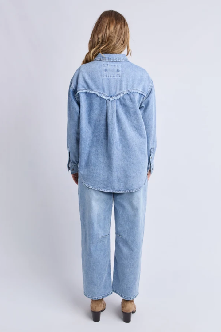 Person wearing a light blue denim outfit on a white background