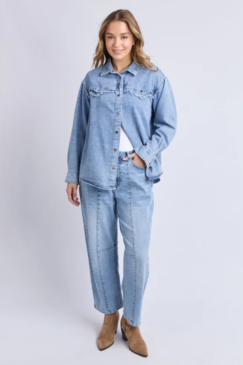 Woman wearing a light blue denim jacket and jeans on a white background