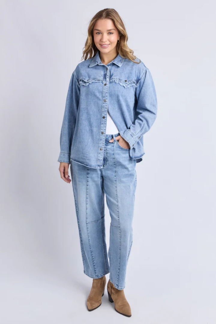 Woman wearing a light blue denim jacket and jeans on a white background
