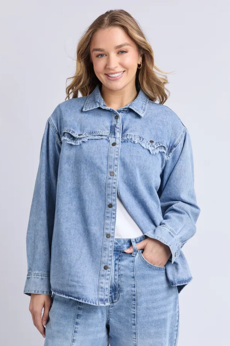 Woman wearing a light blue denim jacket on a plain background