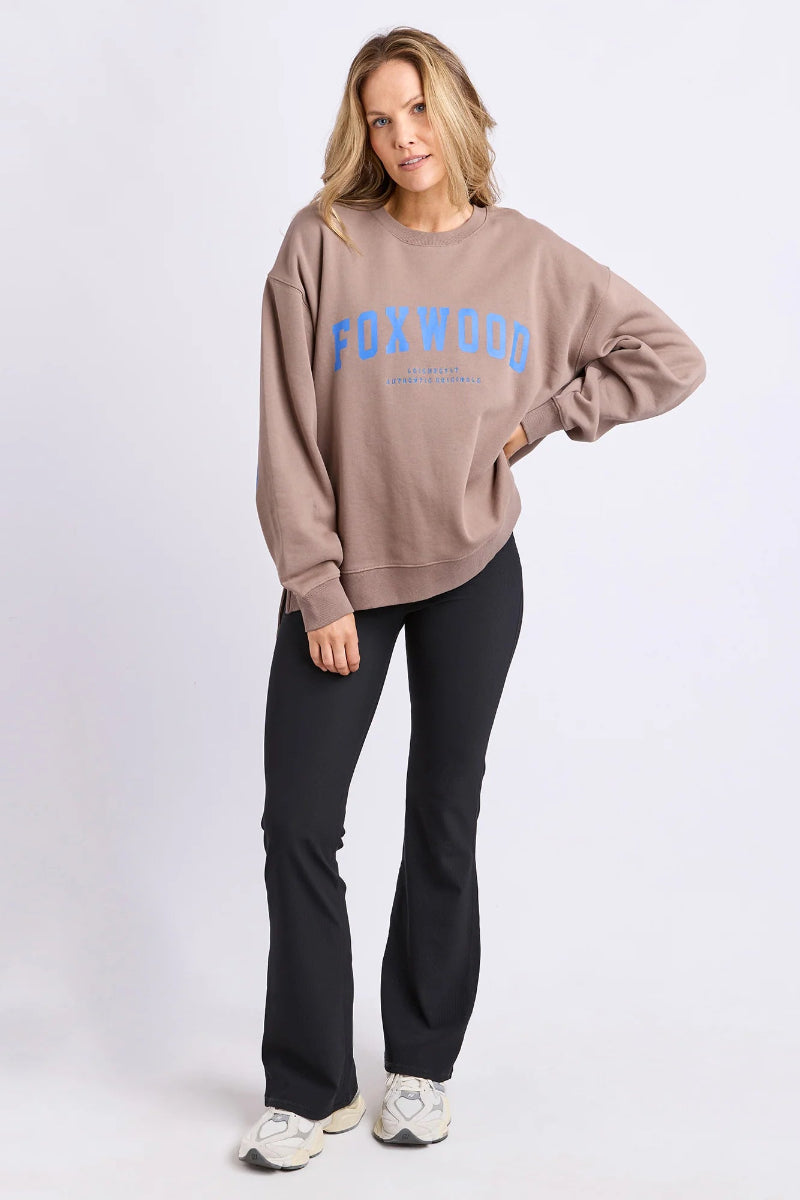 Woman wearing a beige sweatshirt with 'FOXWOOD' text on a white background