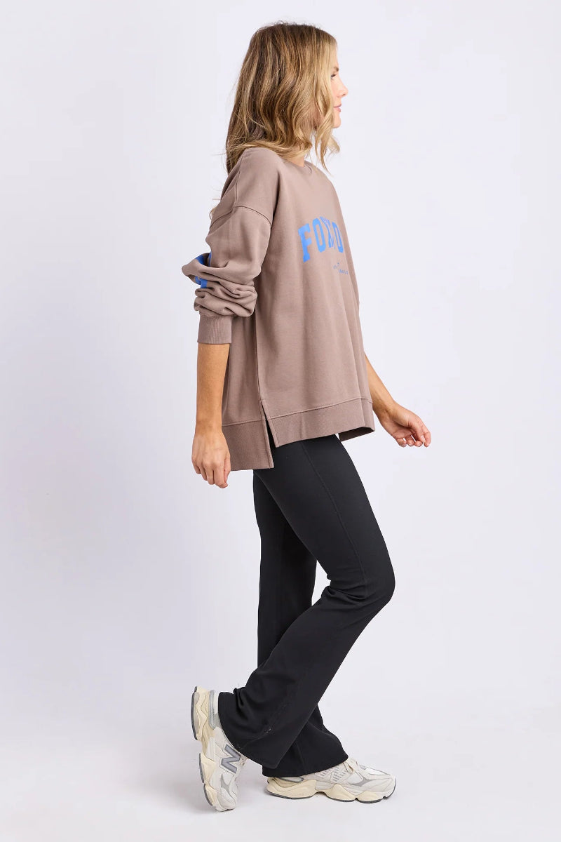 Woman wearing a beige oversized sweatshirt with text on a white background