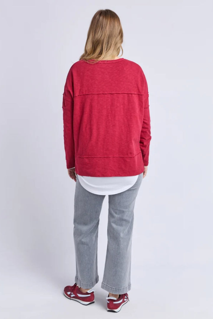 Person wearing a red sweater and gray pants on a white background