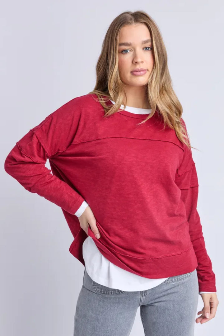 Woman wearing a red sweater, gray pants, and red shoes on a white background