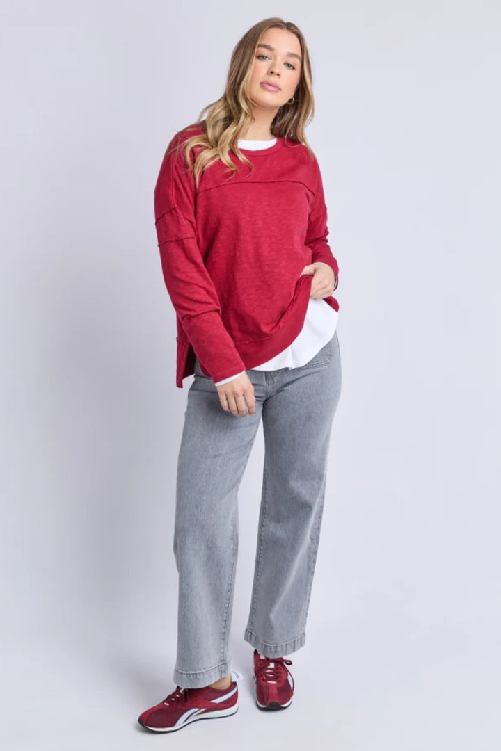 Woman wearing a red sweater, gray pants, and red shoes on a white background
