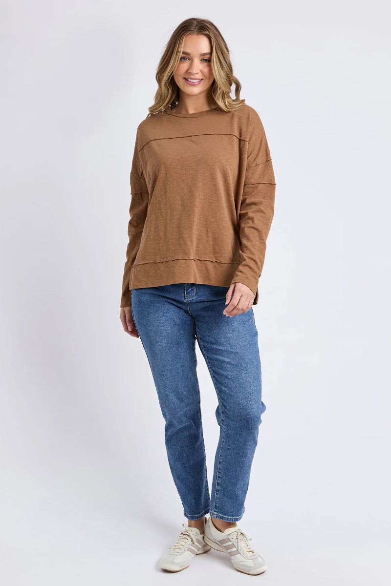 Woman wearing a brown sweater and blue jeans on a white background
