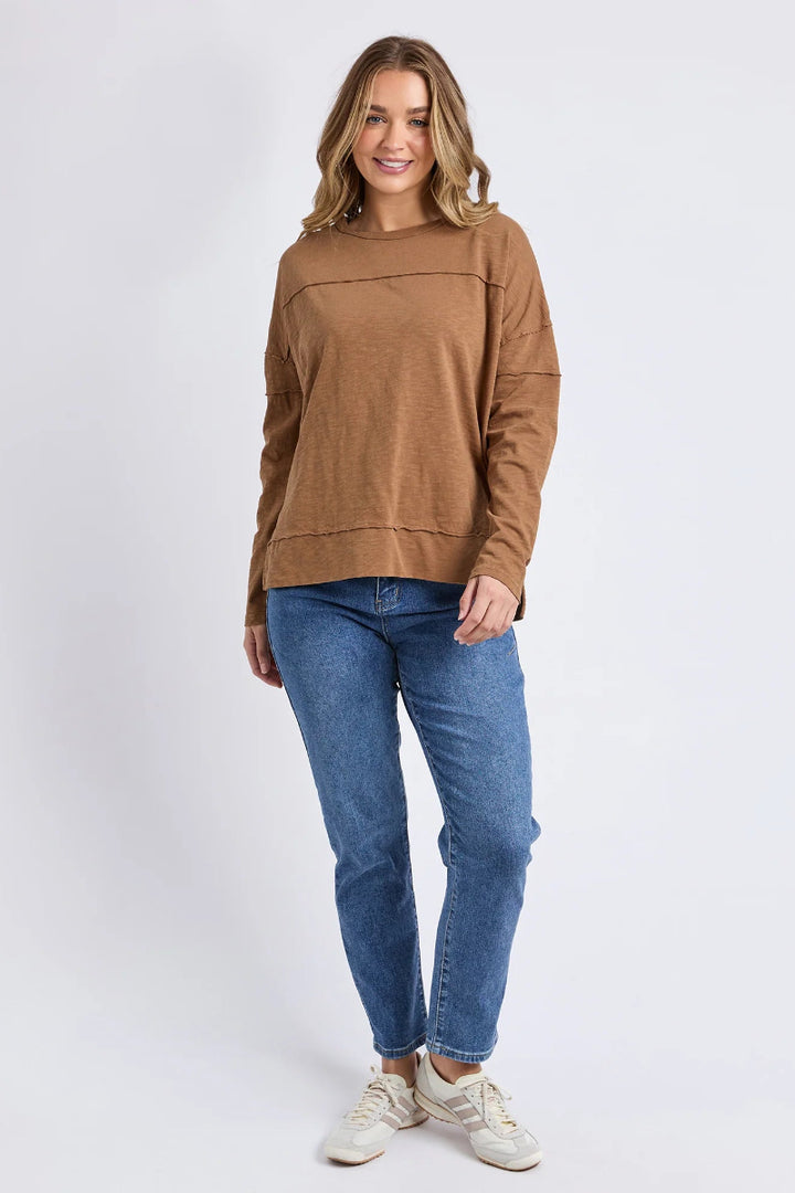 Woman wearing a brown sweater and blue jeans on a white background