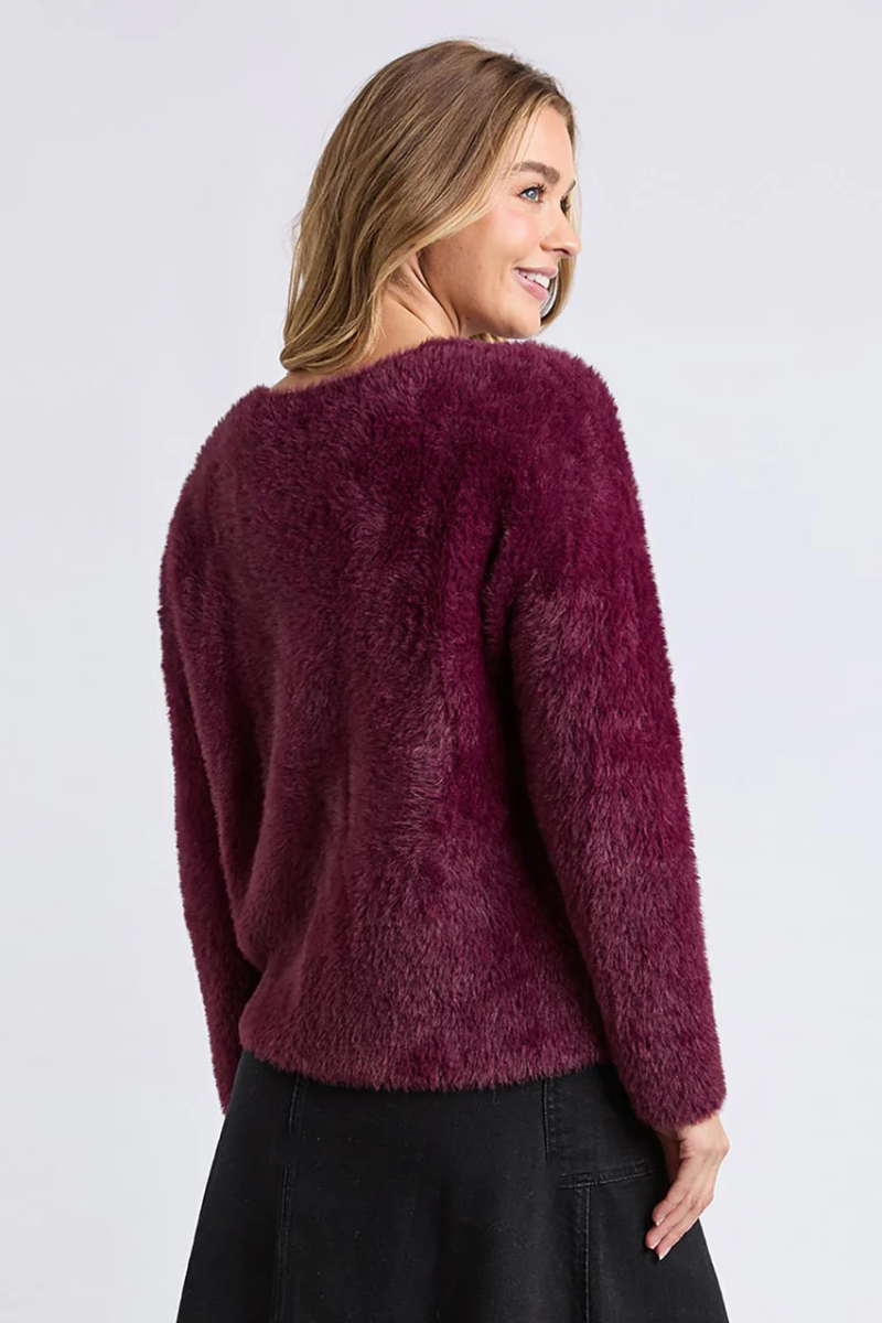 Woman wearing a burgundy fuzzy sweater on a white background