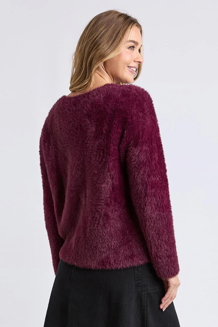 Woman wearing a burgundy fuzzy sweater on a white background
