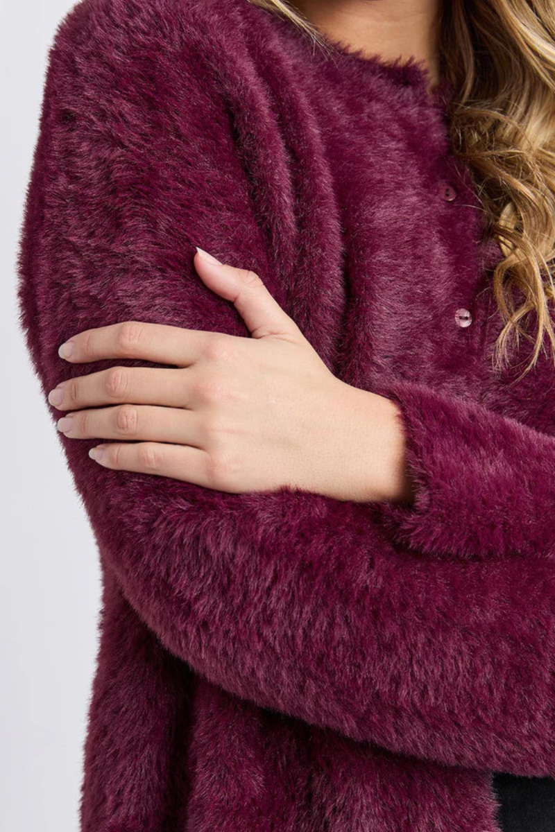 Close-up of a person wearing a fluffy purple sweater with a neutral background