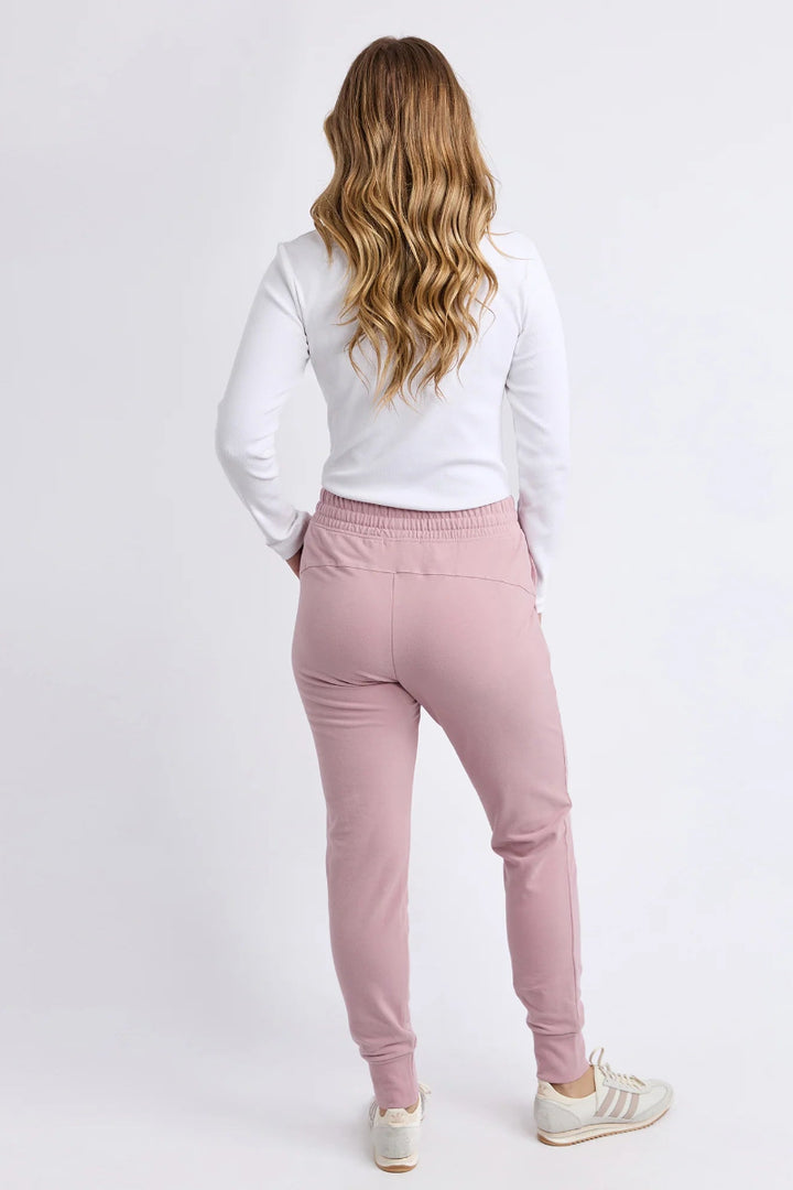 Woman wearing pink pants and a white top on a white background