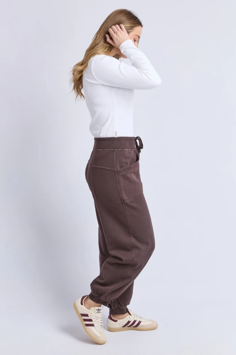 Person wearing brown pants and a white shirt on a light gray background
