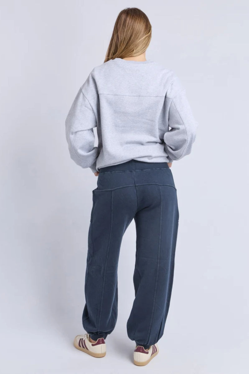 Person wearing a light gray sweatshirt and dark blue pants on a white background