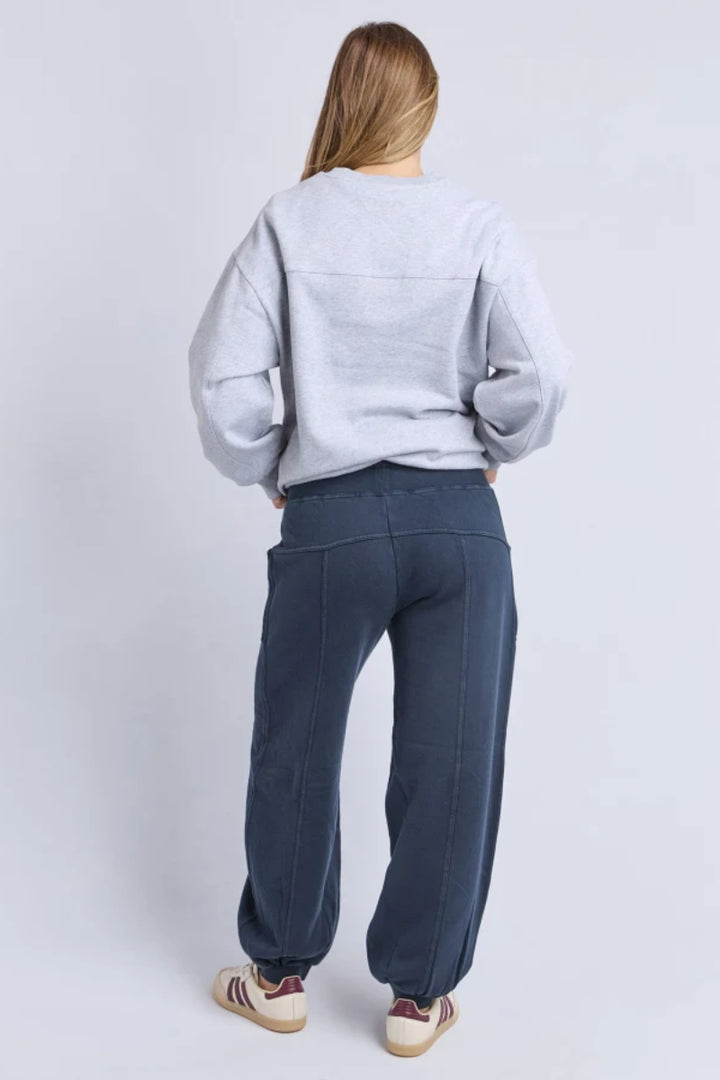 Person wearing a light gray sweatshirt and dark blue pants on a white background